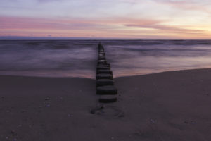 Strand mit Begrenzungspfeilern zu sonnenaufgang